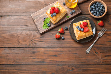 Fototapeta na wymiar Fresh delicious puff pastry with sweet berries on wooden table, flat lay. Space for text