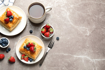 Fresh delicious puff pastry with sweet berries on grey marble table, flat lay. Space for text