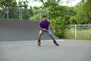 Handsome young man roller skating in park