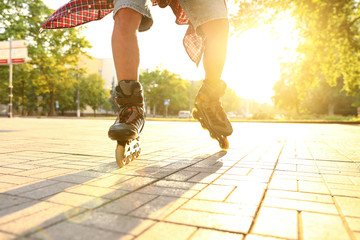 Young man roller skating outdoors on sunny day, closeup. Recreational activity