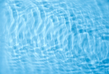 Concentric waves on blue water surface after falling drops, top view