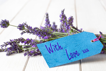 Bunch of lavender flowers,  with love and kisses written on a gift tag label.  White wood background
