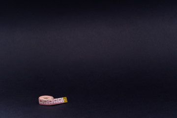 White and red measuring tape on the left on a black background, a tool for measuring length and...