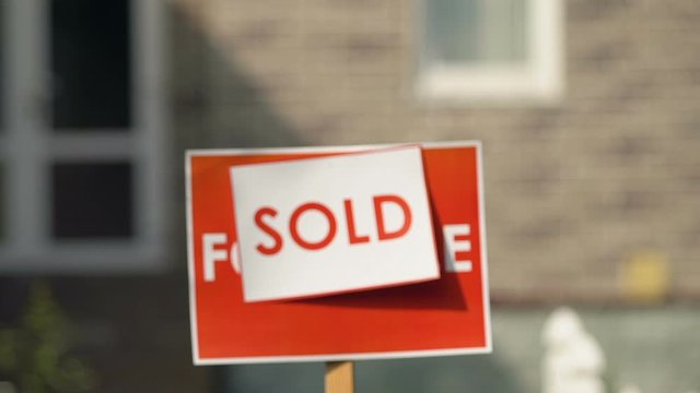 Male hand taking apartment key from broker sold sign background, agency client
