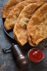 Chebureki or deep-fried turnovers with a filling of minced meat and onion, close-up, selective focus
