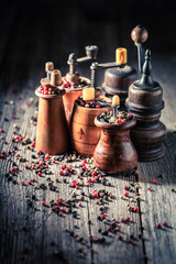 Pepper mills with red and black pepper on wooden table