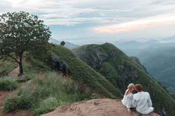 The couple greets the sunrise in the mountains. Man and woman in the mountains. Wedding travel. The...