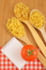 Recipe concept with macaroni, tomato and notepad