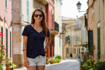 Junge schöne lachende Frau in einer Häuser-Gasse der Altstadt Alcudia Mallorca Spanien Shopping...