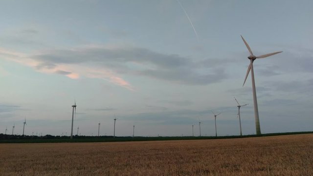 Wind turbines for green energy generation in fast motion time-lapse at dusk in Burgenland plains.