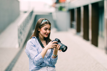 Happy young woman on vacation photographing with camera on the city street