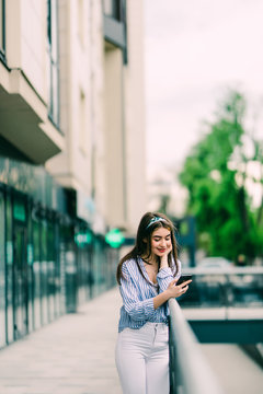 Young girl surfing in phone while leaning on handrail