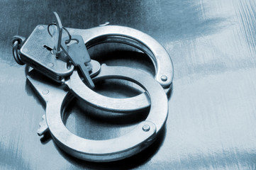 Steel metallic handcuffs with keys on wooden table
