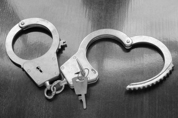 Steel metallic handcuffs with keys on wooden table