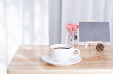 coffee cup and black board  on office table with white curtain background in morning light