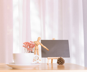 Blank black board with coffee cup and dried flower on office table with white curtain background