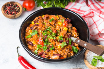 Chili con carne from meat and vegetables on stone table close up.