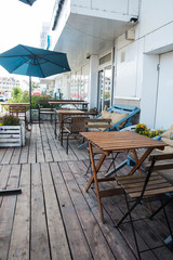 Interior of trendy cafe bistro restaurant, summer outdoor terrace with wooden table and flowers, place settings and decor with copy space.