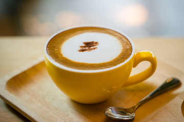 Hot cappucino with small spoon on the table
