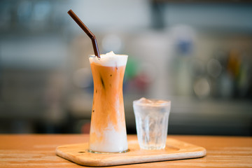 Thai iced milk tea served with a glass of water.