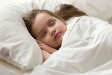 Fototapeta na wymiar Closeup little girl covered with blanket sleeps sweetly in bed