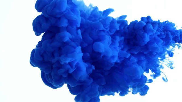 Blue color paint ink drops in water slow motion video with copy space. Inky cloud swirling flowing underwater. Abstract isolated smoke explosion
