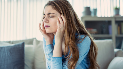 Young woman with headache in home