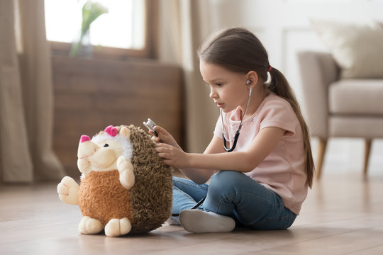 Little girl play doctor and treats hedgehog stuffed toy