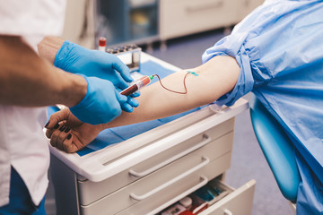 Closeup details of a blood collecting from a young donor , in a modern clinic , collecting the...