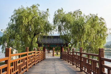 A view of a traditional wooden door with kiwa on the roof at the end of a wooden bridge over the Uirimji Reservoir in Jechun, South Korea.