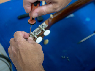 hands of a man repairing a spanish guitar