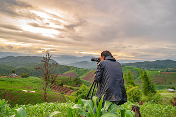 Fototapeta premium Travel photographer with views of the forest and rice fields, mountain, enjoying the beautiful surrounding nature in the cold rainy season.