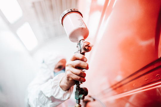 close up of male holding spray gun and painting a car