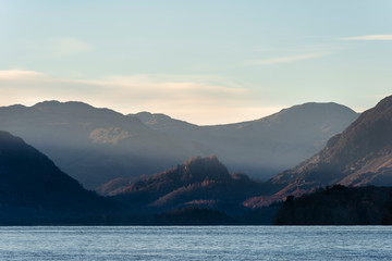 Stunning long exposure landscape image of Derwent Water in Lake District during Autumn Fall sunrise with soft pastel colors