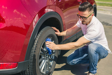 Car detailing - the man holds the microfiber in hand and polishes the car. Selective focus. Car detailing series : Worker cleaning red car. 