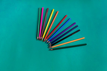 Set of multicolored wooden pencils on a dark blue paper background with copy space. School accessory. Flat lay