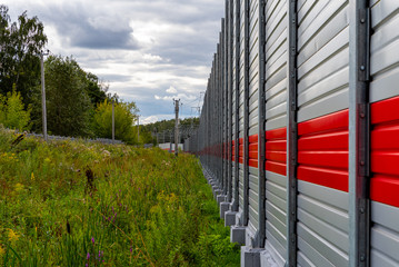 Metal gray fence with red stripe, thick pre-rain clouds and summer colorful landscape