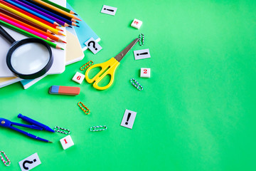 A variety of school supplies notebooks, pencils, scissors, an eraser on a paper green background with space for text. Flat lay