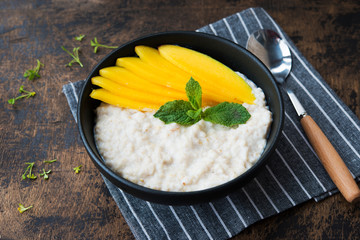 Oatmeal with tropical fruits, mango. Healthy Breakfast bowl.