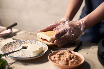 Detailed view of chef preparing gourmet burger with fish, cheese and vegetables. Process of cooking typical italian refreshments. Healthy alternative to grease. Selective focus. Blurred background.