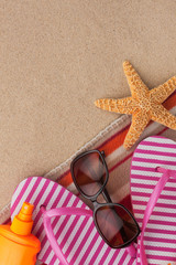 Fototapeta na wymiar Summer accessories flip flops and towel. Sand beach texture background.