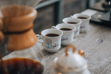 Four white coffee cups on wood table with blurred cafe background