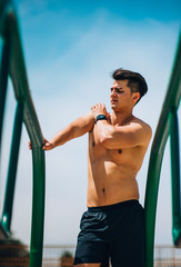 Shirtless sportsman training on parallel bars
