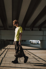 Young man walking under the bridge with backpack