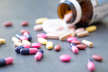 Assorted pharmaceutical medicine and herbal arganic medicine capsules on table dark background.