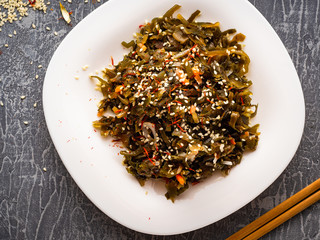 Seaweed salad with sesame seeds is on a white plate