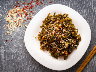Seaweed salad with sesame seeds is on a white plate