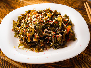 Seaweed salad with sesame seeds is on a white plate