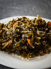 Seaweed salad with sesame seeds is on a white plate