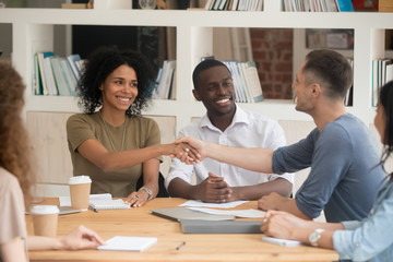 Diverse people starting negotiations shake hands gathered in boardroom